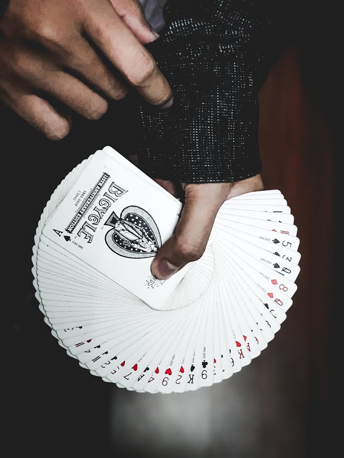 gallery-3 Detailed view of a hand displaying a fan of playing cards indoors, focusing on leisure and card games.