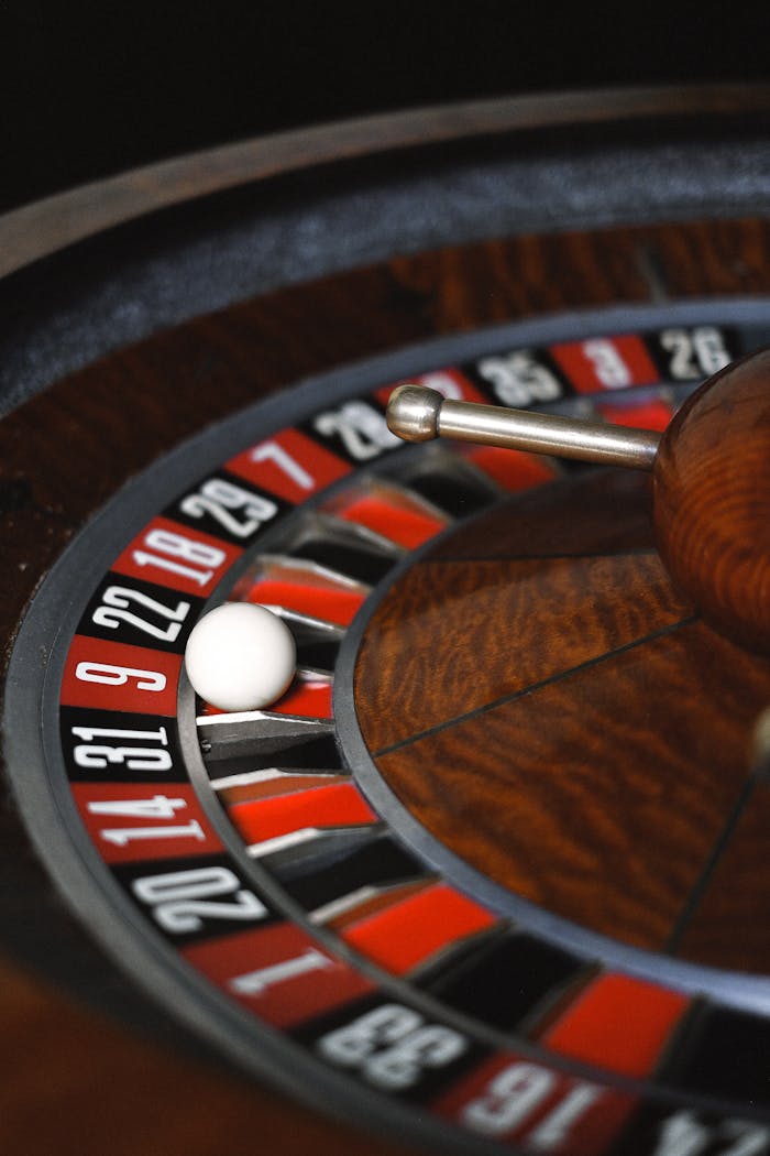 gallery-6 A close-up image of a spinning roulette wheel with a white ball in a casino setting.