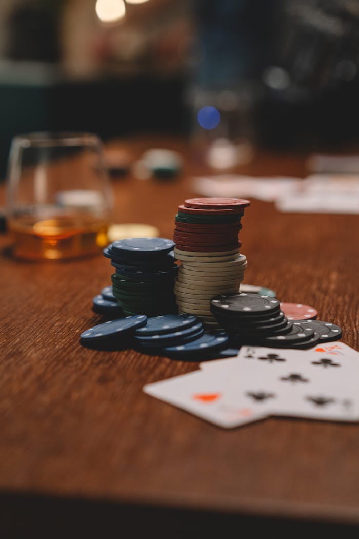 ours-journey Poker chips and playing cards on a wooden table with a whiskey glass, emphasizing gambling and entertainment.