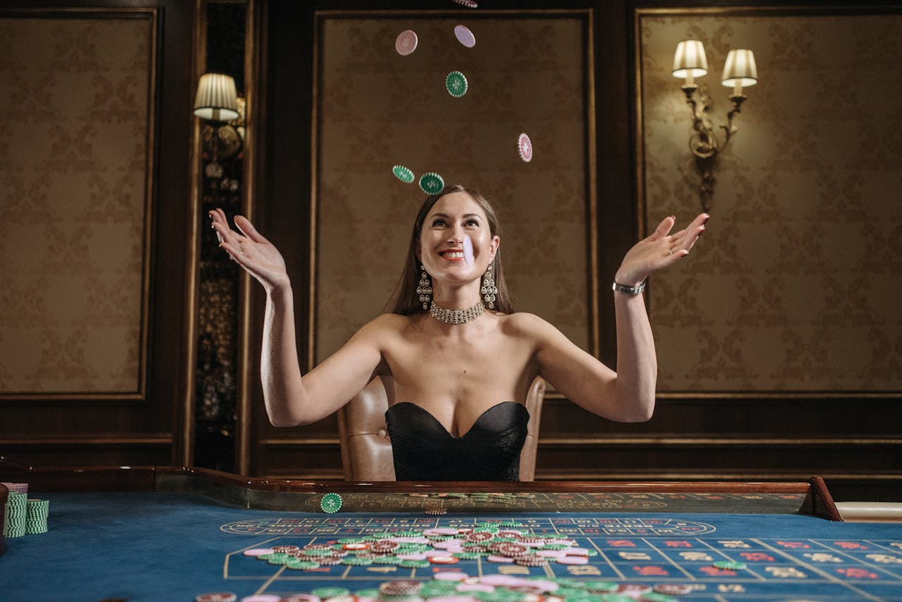 A smiling woman tosses casino chips up in an elegant gaming room, exuding joy.